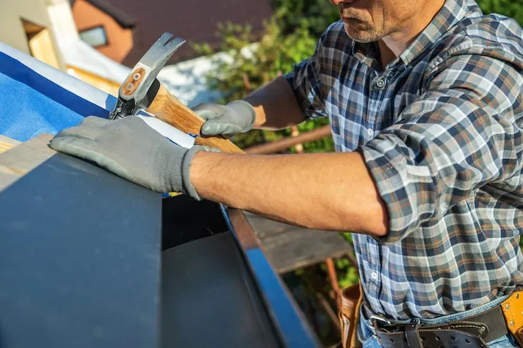 man-working-roof-installation-with-hammer-clear-sky-residential-property